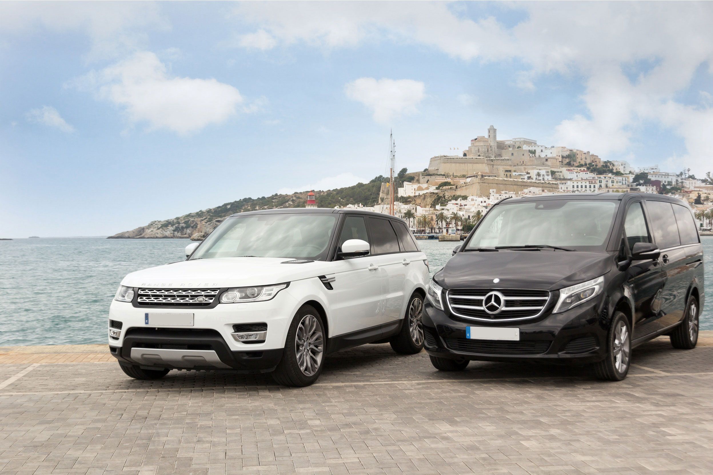 Range Rover and Mercedes V-Class with Ibiza old town landscape